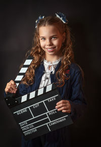 Portrait of young woman standing against black background