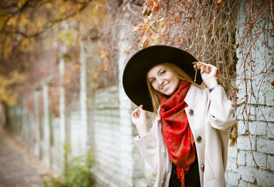 Portrait of smiling young woman standing against tree