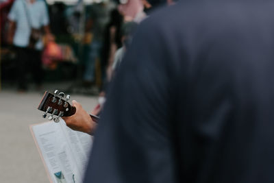 Hidden view of busker playing guitar in a market place