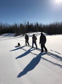 People on snow covered field against sky