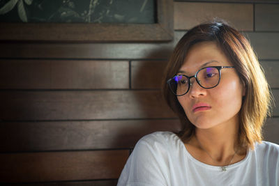 Thoughtful woman against wall at home