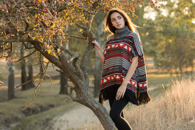 Young woman standing against trees