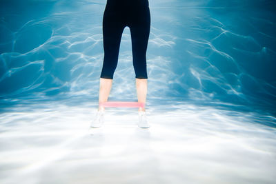 Low section of woman standing in swimming pool