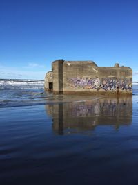 Built structure in sea against blue sky