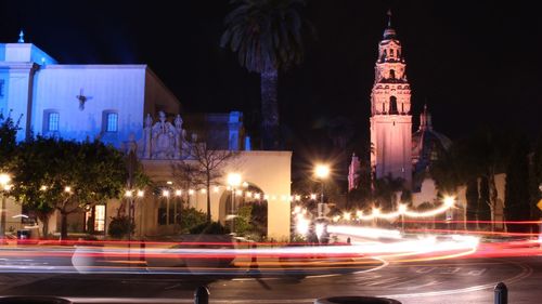 Light trails on street against illuminated buildings in city at night