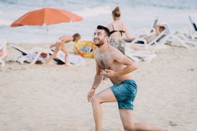 Full length of shirtless man at beach