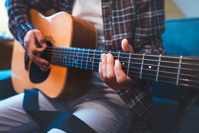 Midsection of man playing guitar