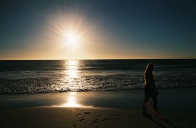 Woman on beach against sky during sunset