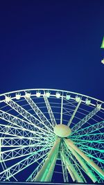 Low angle view of illuminated ferris wheel against clear blue sky