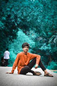 Portrait of young man sitting against plants