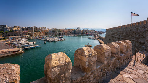 Boats in harbour against clear sky