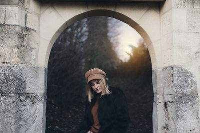 Portrait of woman standing against brick wall