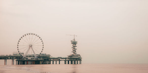 Ferris wheel by sea against clear sky