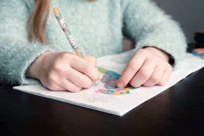 Midsection of woman holding paper with hand on table