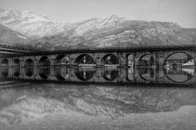 Bridge over river against mountains during winter