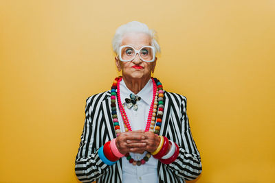 Portrait of smiling young man against yellow background