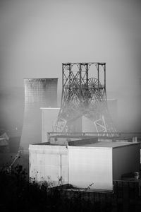 Ferris wheel by building in city against sky