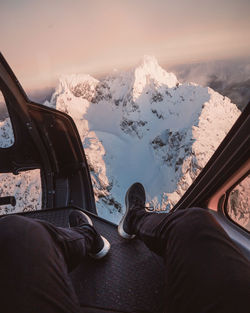 Low section of person in air vehicle over snowcapped mountain