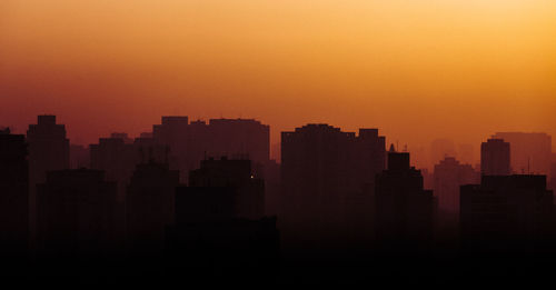 Silhouette buildings against sky during sunset