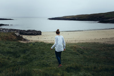 Rear view of woman on beach against sky