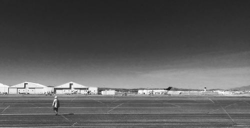 Rear view of man at airport runway against sky