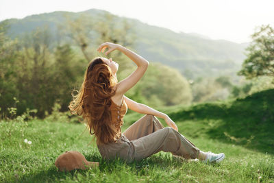 Rear view of woman sitting on field