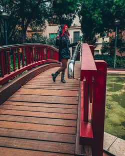 Rear view of woman walking by railing against trees