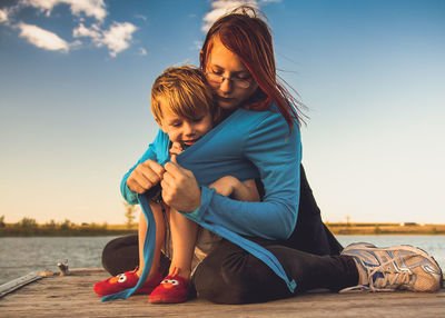 Mother and son at sea shore against sky