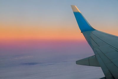 Airplane flying over sea against sky during sunset