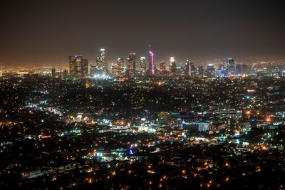 Illuminated cityscape against sky at night