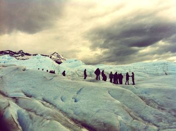 Group of people on snow covered mountain against sky