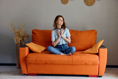 Portrait of young woman sitting on sofa at home