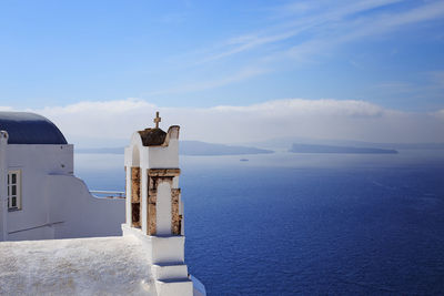 Lighthouse amidst sea and buildings against sky