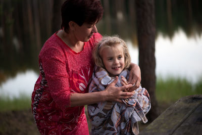 Mother covering daughter with blanket on field