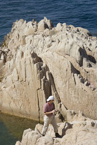 High angle view of man standing on cliff by sea