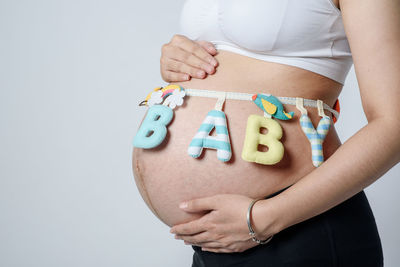 Midsection of woman holding hands against white background