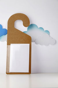 Close-up of blank door tag against clouds on white background