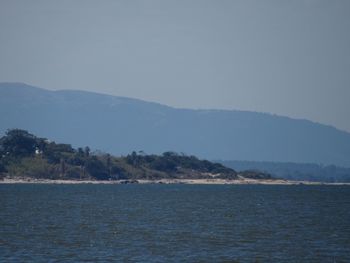 Scenic view of sea and mountains against clear sky