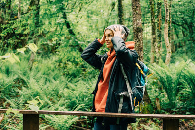 Young caucasian woman in a raincoat and a hat in the thickets of the forest