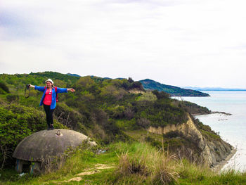 Woman with arms outstretched standing against sea at beach