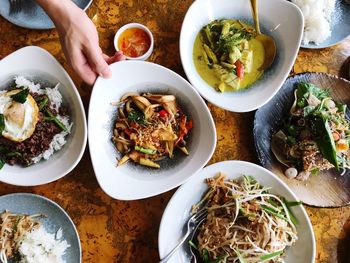 Cropped image of hand holding food in bowl during lunch