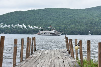 Pier on lake by mountains against sky