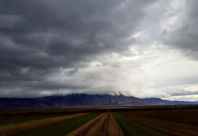 Scenic view of field against storm clouds