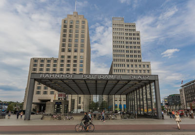 People walking on modern building against sky