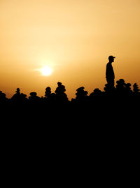 Silhouette people sitting against clear sky during sunset
