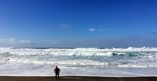 Rear view of a man on the beach contemplating the waves