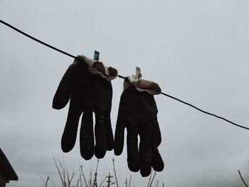 Low angle view of men hanging on rope against clear sky