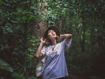 Young woman standing against trees in forest