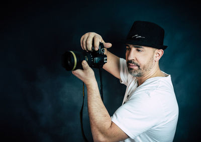 Close-up of man photographing through camera against wall