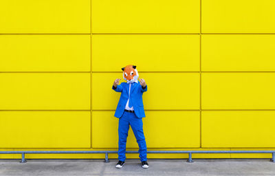 Portrait of a man standing against yellow wall